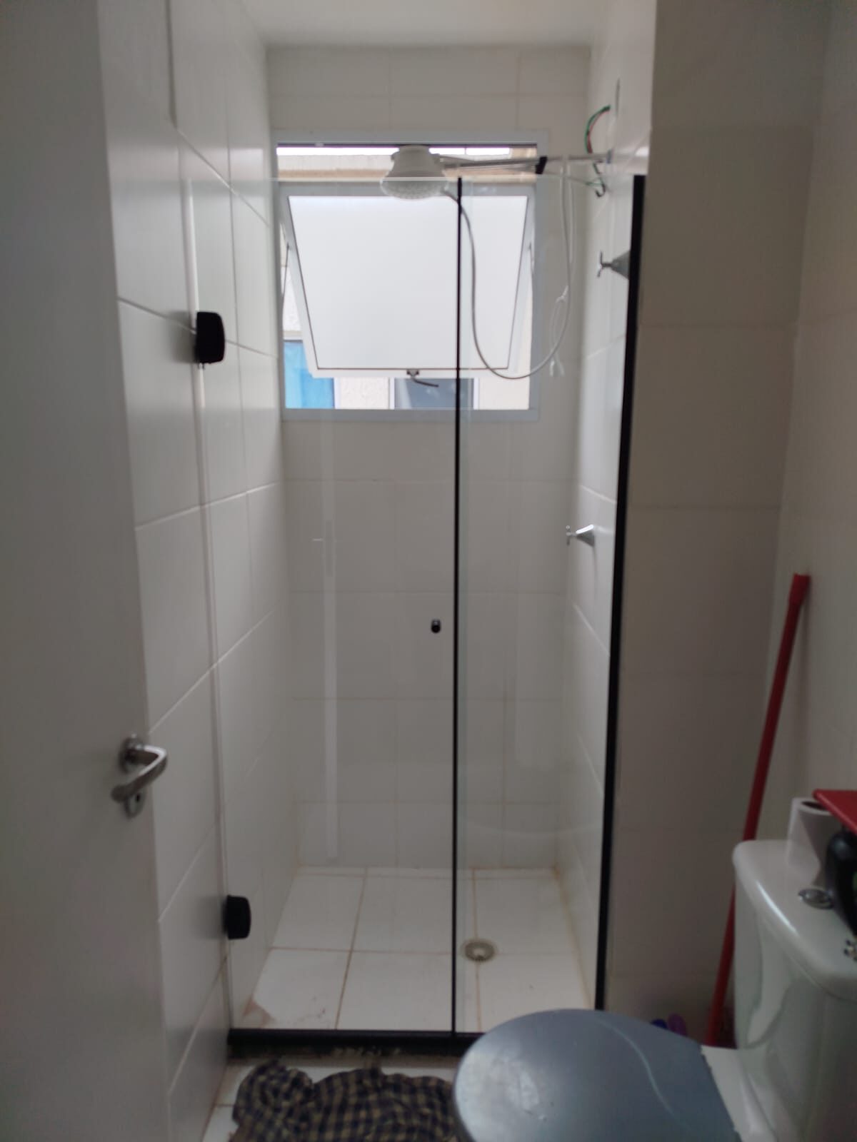 Box de vidro incolor com puxador preto em banheiro claro