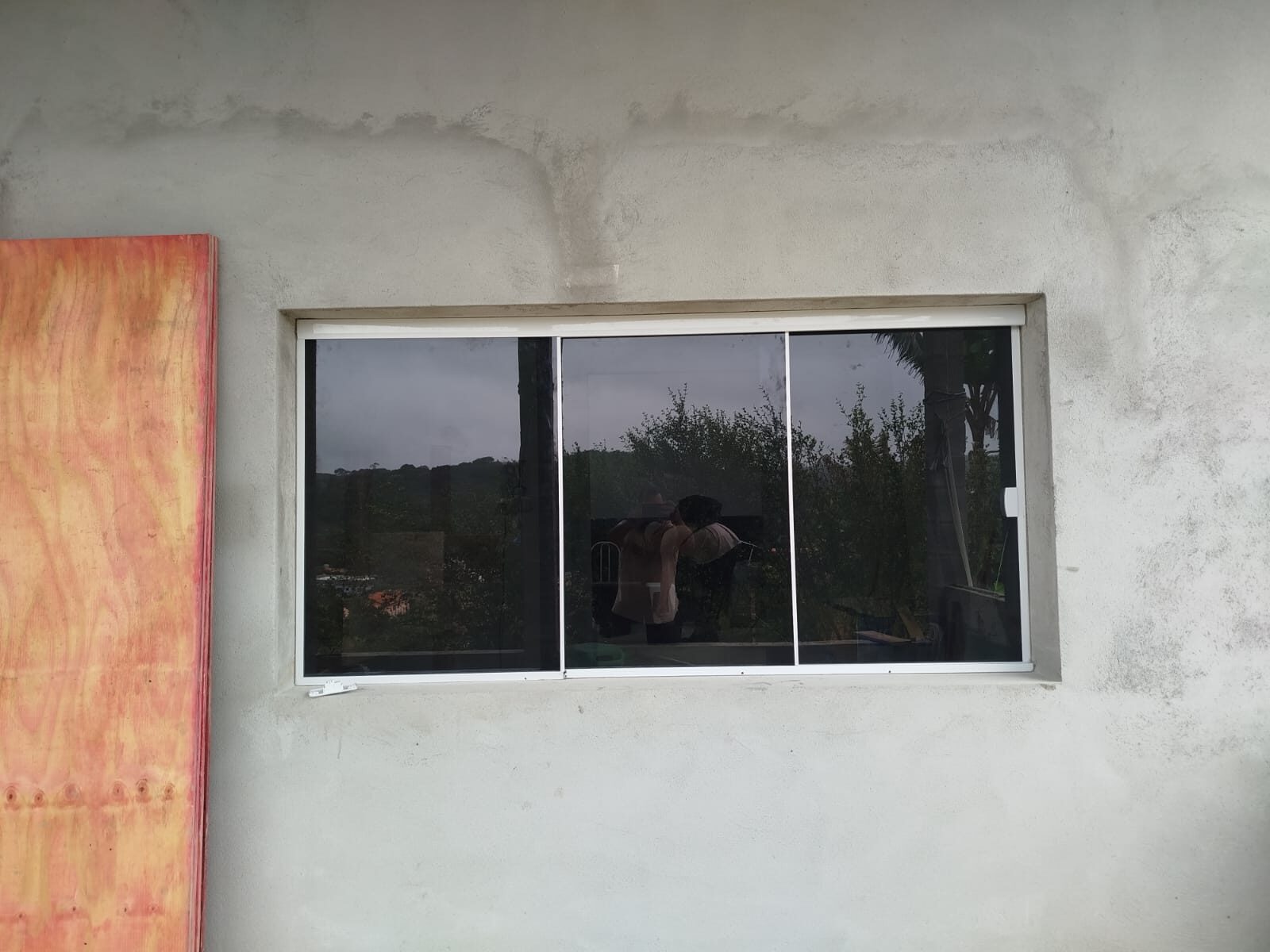 Janela de correr em vidro e alumínio em parede de concreto