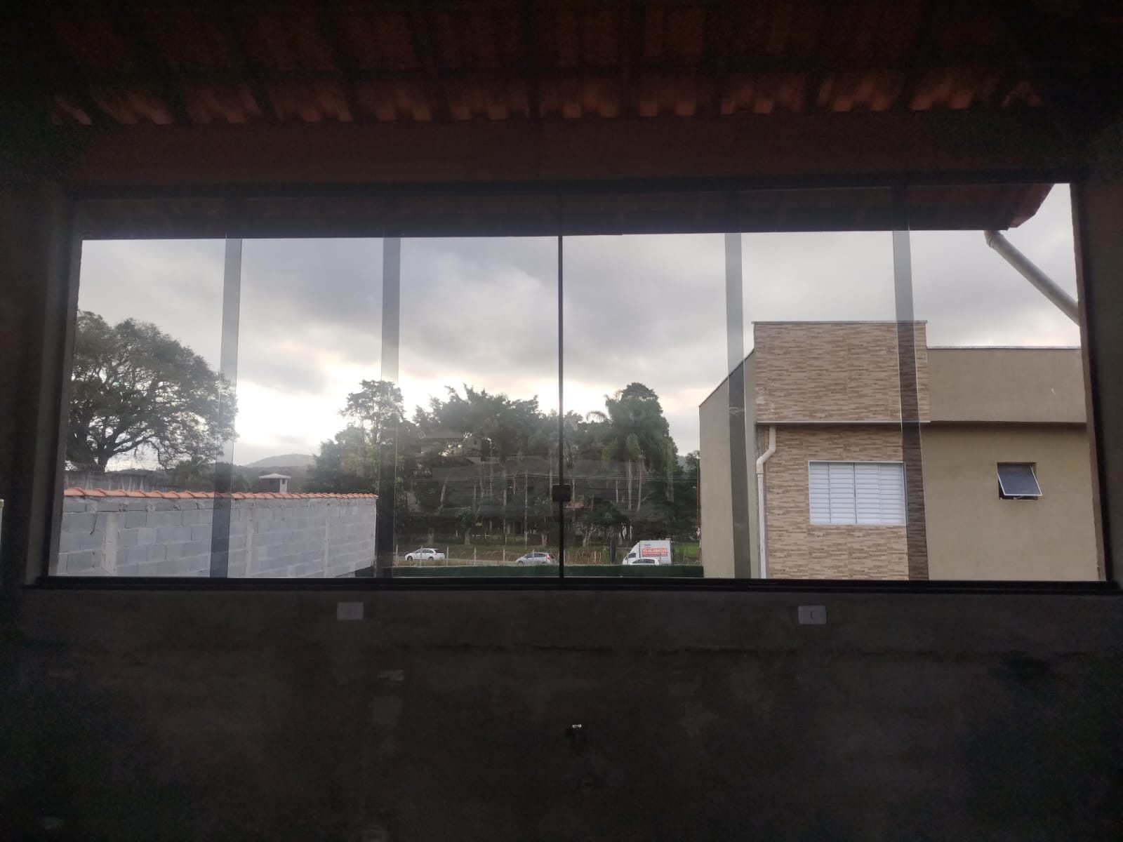Sacada envidraçada com perfis de alumínio preto e vista para o quintal
