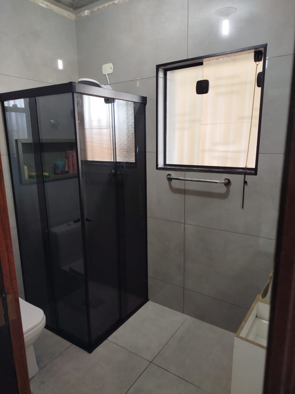 Box de vidro fumê com perfil preto em banheiro compacto