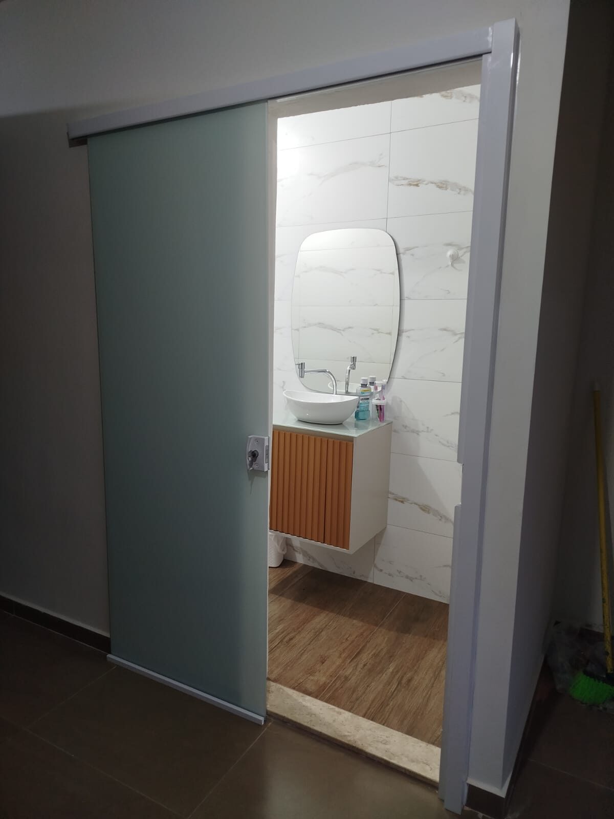 Porta de correr em vidro jateado dando acesso ao lavabo